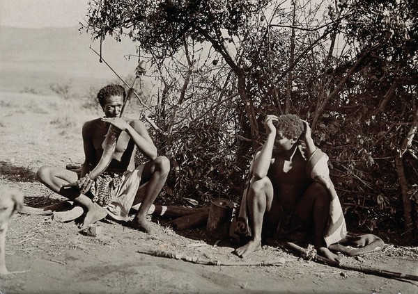 Swaziland: two young men seated, one of them smoking hemp (cannabis) through a pipe made with a horn. Photograph.