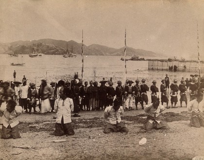 Kowloon, Hong Kong: five pirates awaiting beheading, while Chinese soldiers and dignitaries line up behind. Photograph, 1891.