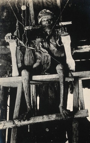 view Philippines: the dead body of a wealthy man displayed seated on a high chair after having been smoked for 24 days. Photograph, 19--.