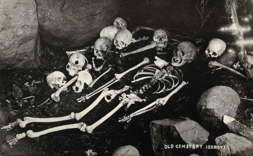Philippines: skulls and a skeleton of the dead lying on the ground. Photograph, 19--.