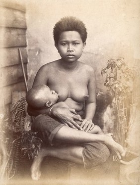 Thailand: a woman breastfeeding her child seated cross-legged: studio portrait (?). Photograph, 1880/1900.