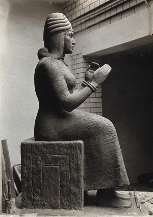 view A sculpture of Gula, Mesopotamian deity of healing, with a dog at her side. Photograph.