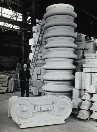 The Wellcome Research Institution building, Euston Road, London: Septimus Warwick beside a pile of carved stone for the new building, 1931. Photograph.
