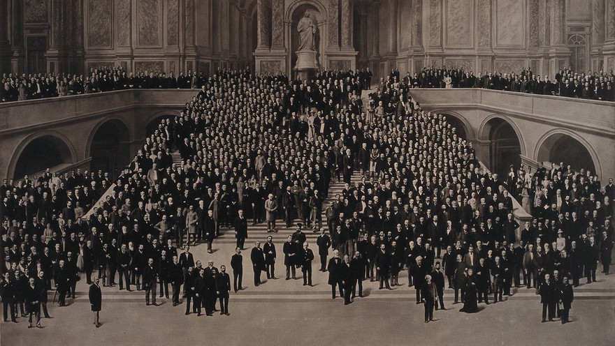 Seventh International Congress of Hygiene and Demography, London: participants standing on a monumental staircase with a statue of Queen Victoria in a niche at the top. Photograph by Barrauds, 1891.