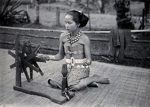 Sarawak: a girl spinning cotton into thread. Photograph.