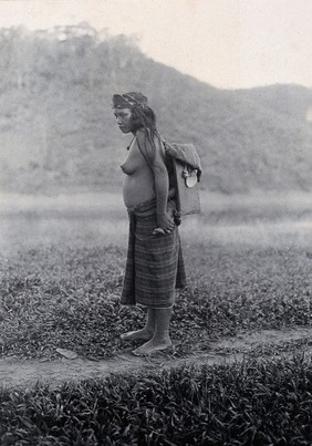 Sarawak: a Kayan woman carrying her child in a sling. Photograph.