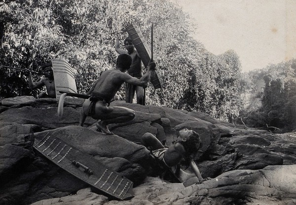 Sarawak: four Dayak men in a warfare ritual. Photograph.