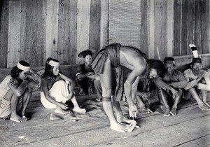 view Sarawak: a Kayan man making fire by rubbing cane on wood. Photograph.