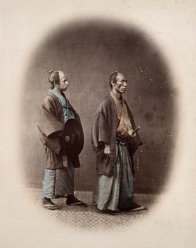 Japan: two samurai in traditional robes with swords. Coloured photograph by Felice Beato, ca. 1868.