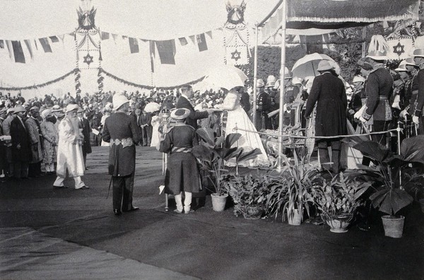 Prinsep Ghat, Calcutta, India: the Princess of Wales (later Queen Mary), holding a parasol and accepting a jewel from the Chairman of the Calcutta Municipal Corporation, in front of a crowd of onlookers. Photograph, 1906.