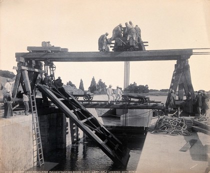 Menufia Canal, Egypt: reconstruction work to the first Aswan Dam: men at work lowering a metal lock gate (?) into the dam. Photograph by F. Fiorillo, 1910.