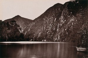 view Knysna Lakes, South Africa: a lake with a boat and hills. Woodburytype, 1888, after a photograph by Robert Harris.