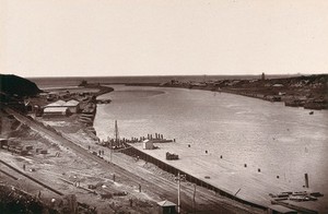 view East London, South Africa: a jetty and buildings near the mouth of the Buffalo River. Woodburytype, 1888, after a photograph by Robert Harris.