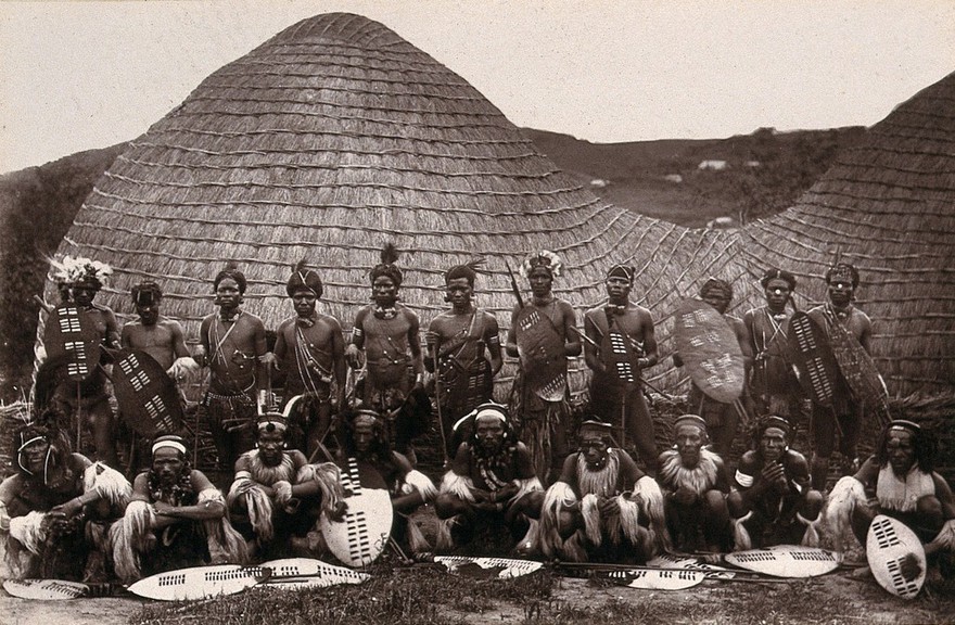 Zululand, South Africa: a group of Zulu men in war dress. Woodburytype, 1888, after a photograph by Robert Harris.