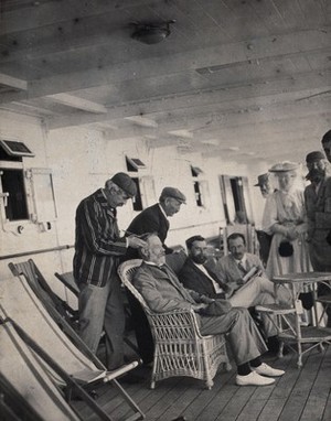 view Members of the British Association playing at phrenology on board a ship on its way to South Africa. Photograph by J.T. Bottomley, 1905.