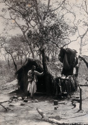 Zimbabwe: an African man standing in front of a hut, in a village near Umtali. Photograph by Sir William Crookes, 1905.