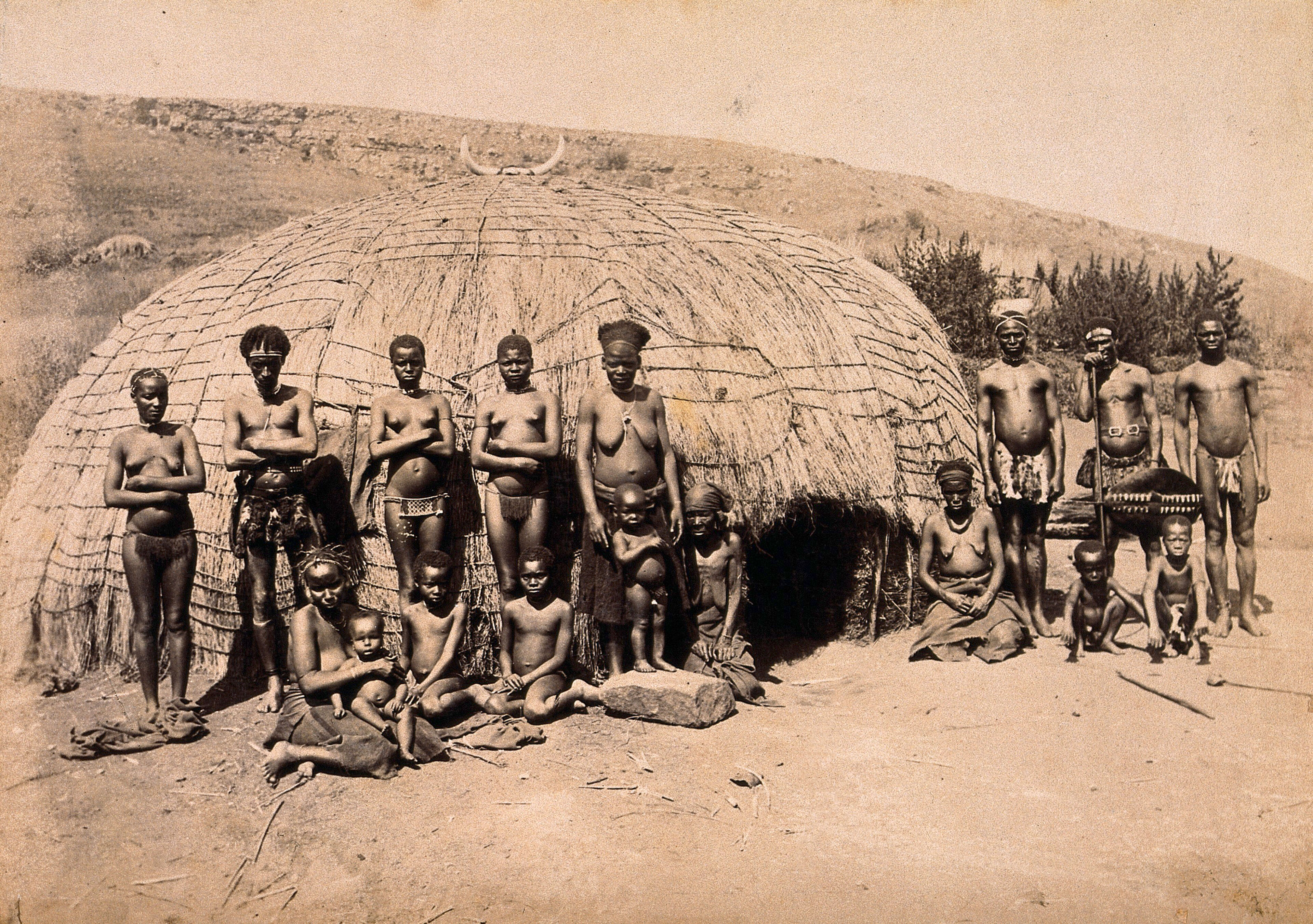 South Africa: Africans in front of a traditional kraal hut. Albumen print.