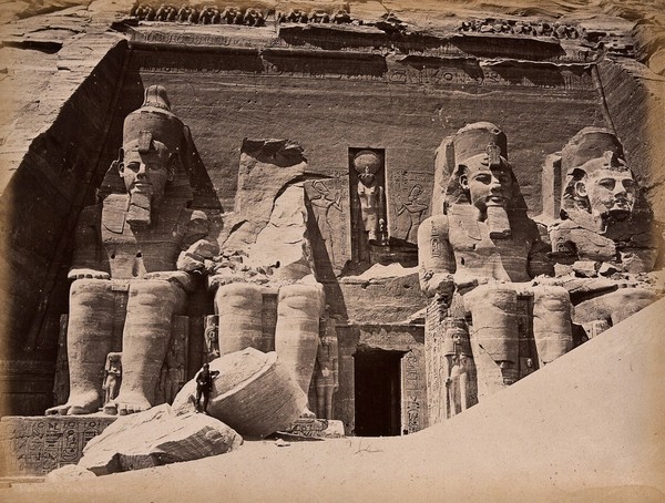 The Abou Simbel temple (the Sun Temple of Ramesses II), Nubia, Egypt: four seated colossi of Ramesses II; a man stands in the foreground as an indication of scale. Photograph by Pascal Sébah, ca. 1875.