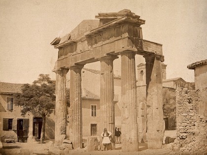 Athens: the gate of Athena Archegetis in the Roman Agora, Athens; a man in traditional Greek dress poses in the foreground. Photograph by Petros Moraites, ca. 1870.