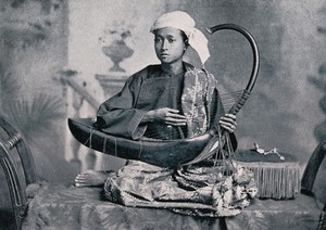 view A boy playing a saung or Burmese harp. Process print.