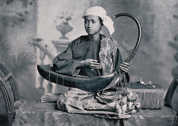 A boy playing a saung or Burmese harp. Process print.