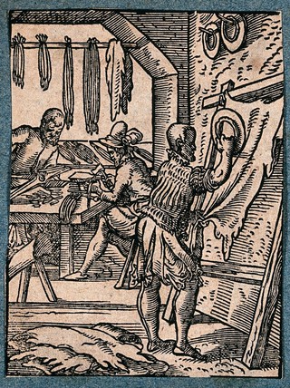 A maker of coloured laces cuts an animal hide into strips; his colleagues hammer tags on to the laces. Woodcut by J. Amman.