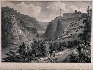 view Crowds of people are standing on hillsides looking down on to a river in the valley over which the Clifton suspension bridge was to be built. Lithograph.