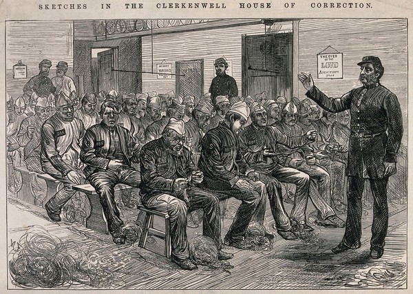 Middlesex House of Correction: prisoners sitting on long benches untangling bundles of twine (picking oakum); a guard raises his hand. Wood engraving. after M. Fitzgerald, 1874.