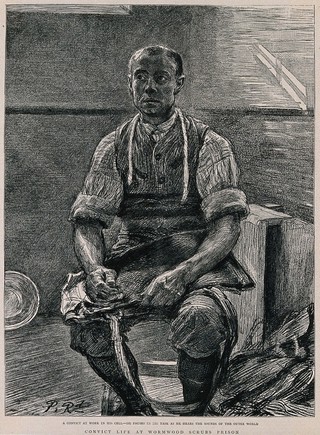 Wormwood Scrubs Prison: a convict sitting in a bare room on a stool with some work in his hands. Process print after Paul Renouard.