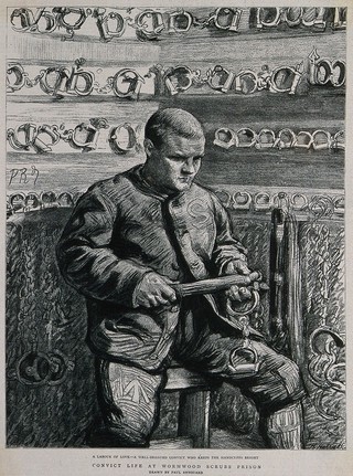 Wormwood Scrubs Prison, London: a prisoner in the chain-room where manacles are stored: he is cleaning them. Process print after Paul Renouard.