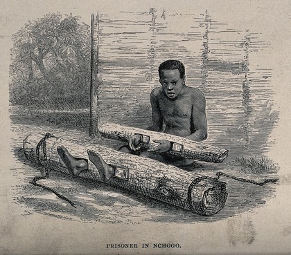 A man in Africa sitting imprisoned on the ground, with his hands and feet locked into holes made in cut-down tree trunks. Wood engraving after P.B. Du Chaillu, 1867.