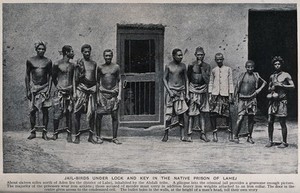 view Nine male prisoners In Yemen wearing leg irons. Process print.