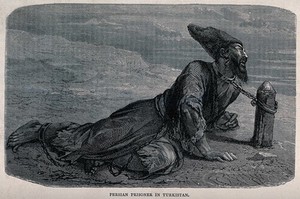 view A Persian captive lying on the road chained by his neck to a post embedded in the road. Wood engraving.