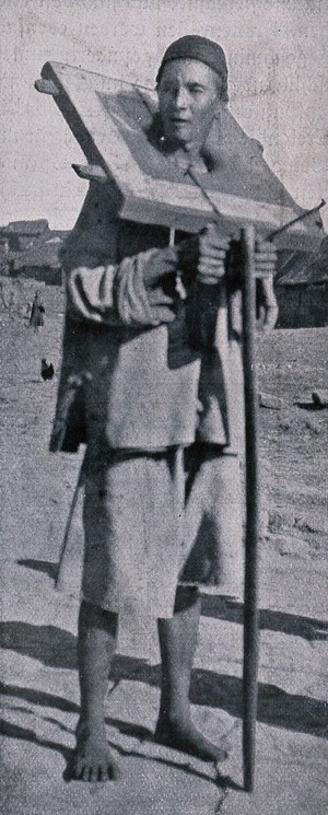 view A Chinese man stands carrying the cangue around his neck as a punishment. Process print after a photograph.