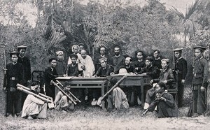 view Hanoi, Vietnam: four seated men restrained by the cangue round their necks are being tried for violent crimes by the tribunal of the French resident; armed guards standing by. Wood engraving by H. Thiriat, 1889, after C.E. Hocquard.