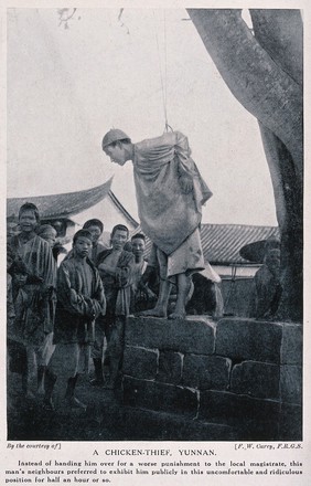 A chicken-thief in Yunnan Province, China, punished by being attached to a tree by his arms, watched by a crowd of people. Halftone after F.W. Carey.