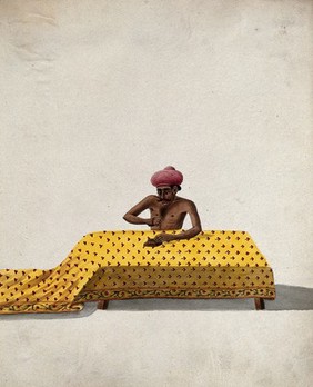 A man engaged in block printing a piece of cloth. Gouache painting by an Indian artist.