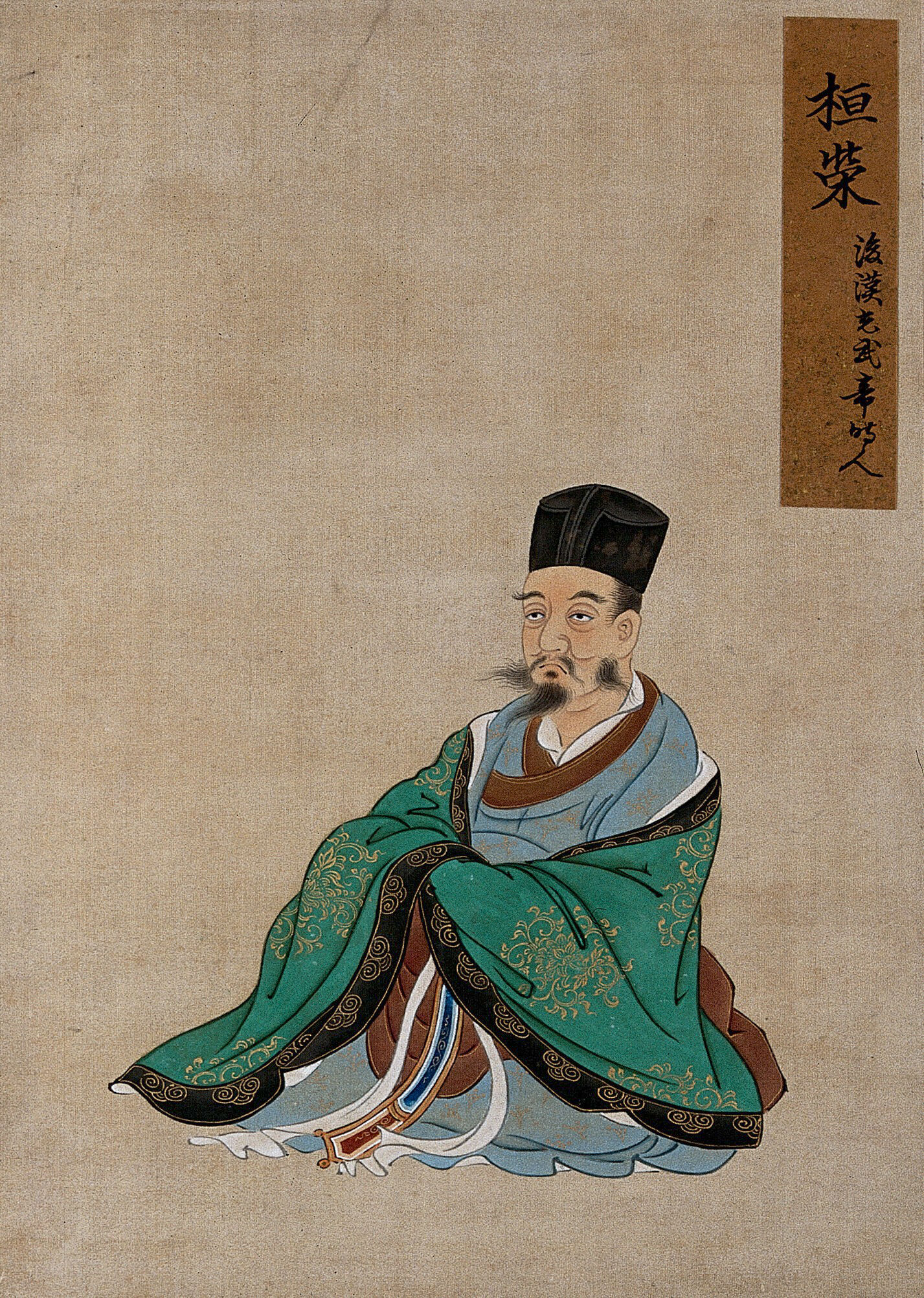 A Chinese Figure, Seated, Wearing Green Robes With Black Border And 