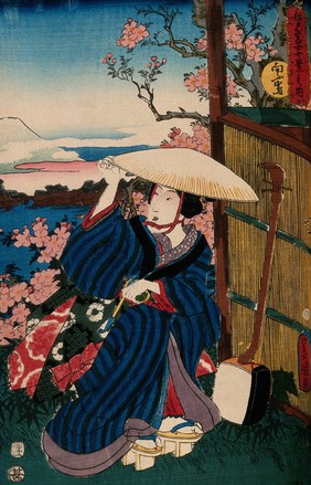 A kneeling woman in a broad straw hat, holding a pipe; a shamisen rests against the reed fence to the right; the view behind is a view of Fuji from Mukōjima. Colour woodcut by Kunisada, 1854.