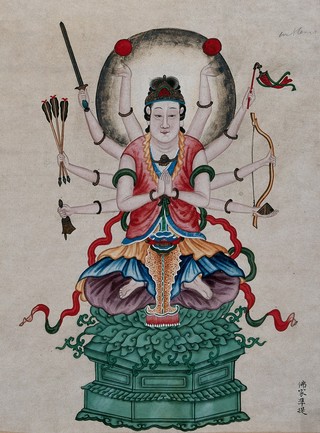 A Chinese deity identified as Kuan Yin, seated in the lotus position on a jade throne, with ten arms, carrying weapons, a bell and round objects. Painting by a Chinese artist.
