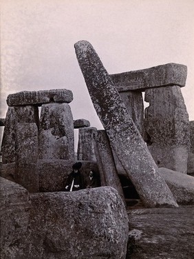 Stonehenge, England: view of leaning stone (right), prior to staightening; two members of the Society of Antiquaries seated amongst stones. Photograph, 1901.