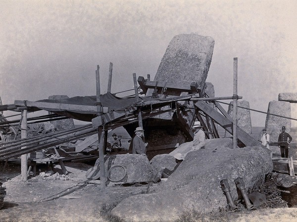 Stonehenge, England: Professor William Gowland (centre) watching the straightening of a leaning stone which is attached to a wooden frame and pulleys. Photograph, 1901.