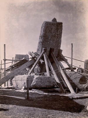 view Stonehenge, England: the straightening of a leaning stone which is attached to a wooden frame and supported by beams: north east view. Photograph, 1901.