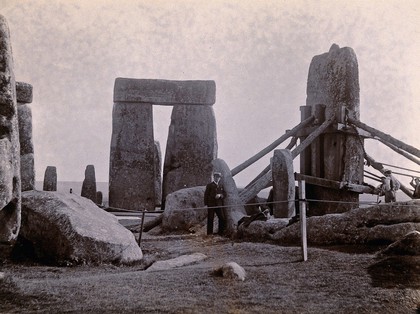 Stonehenge, England: the straightening of a leaning stone which is attached to a wooden frame and supported by beams: raised upright. Photograph, 1901.