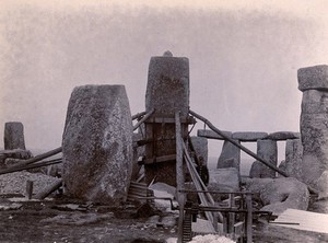 view Stonehenge, England: the straightening of a leaning stone which is attached to a wooden frame and supported by beams and pulleys: raised upright. Photograph, 1901.