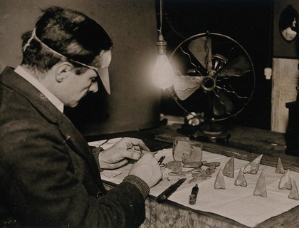 Prostheses: artificial noses being made by an artist at work in his studio in Hampstead, London. Photograph, ca. 1921.