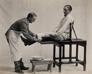 view A doctor bandages the stump of a man missing his leg below the knee. Photograph, 1914/1918.