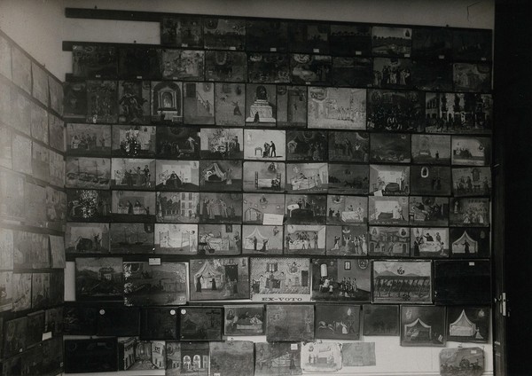 Votive offerings: small paintings, mainly of accident and recovery scenes, displayed at the Ethnographic Museum, Palermo, Sicily. Photograph, 1929.