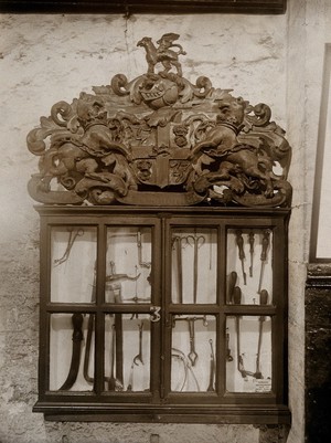 view The Barber Surgeons' Guild of Newcastle: surgical instruments in a display case bearing the Guild's coat of arms. Photograph, ca. 1900.