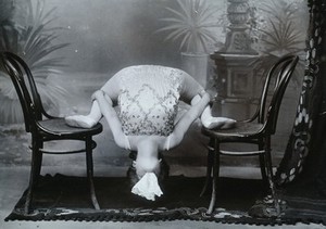 view A Bulgarian female acrobat performing contortions with a handkerchief in her mouth.